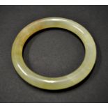 A Chinese jade bangle of mottled pale yellow-green colour