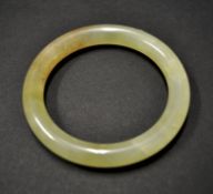 A Chinese jade bangle of mottled pale yellow-green colour