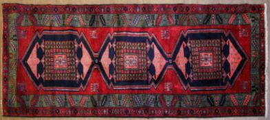 An Azari red-ground rug, woven with geometric dark-blue,
