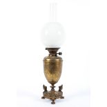 A late 19th century brass oil lamp, the urn shaped body with embossed foliate decoration,