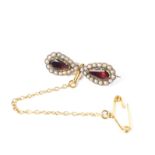 A 19th century 9ct gold garnet and seed pearl bow brooch set with two pear cut foil backed garnets