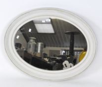 A large contemporary wall mirror of oval form, white painted