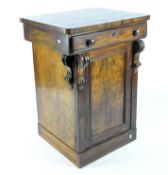 A mahogany side cabinet, the carved door opening to reveal two interior shelves,