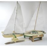 A wooden model of a yacht and one of a katamaran, both boats are decorated in cream and green,