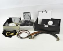 An assortment of belts, mostly leather, some with designer buckles,