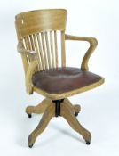 A vintage oak captain's swivel chair, with adjustable studded leather seat,