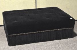A large upholstered footstool of rectangular form, upholstered in black velvet,