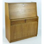 A mid-20th century teak retro style bureau, with a fall front above two drawers and a cupboard,