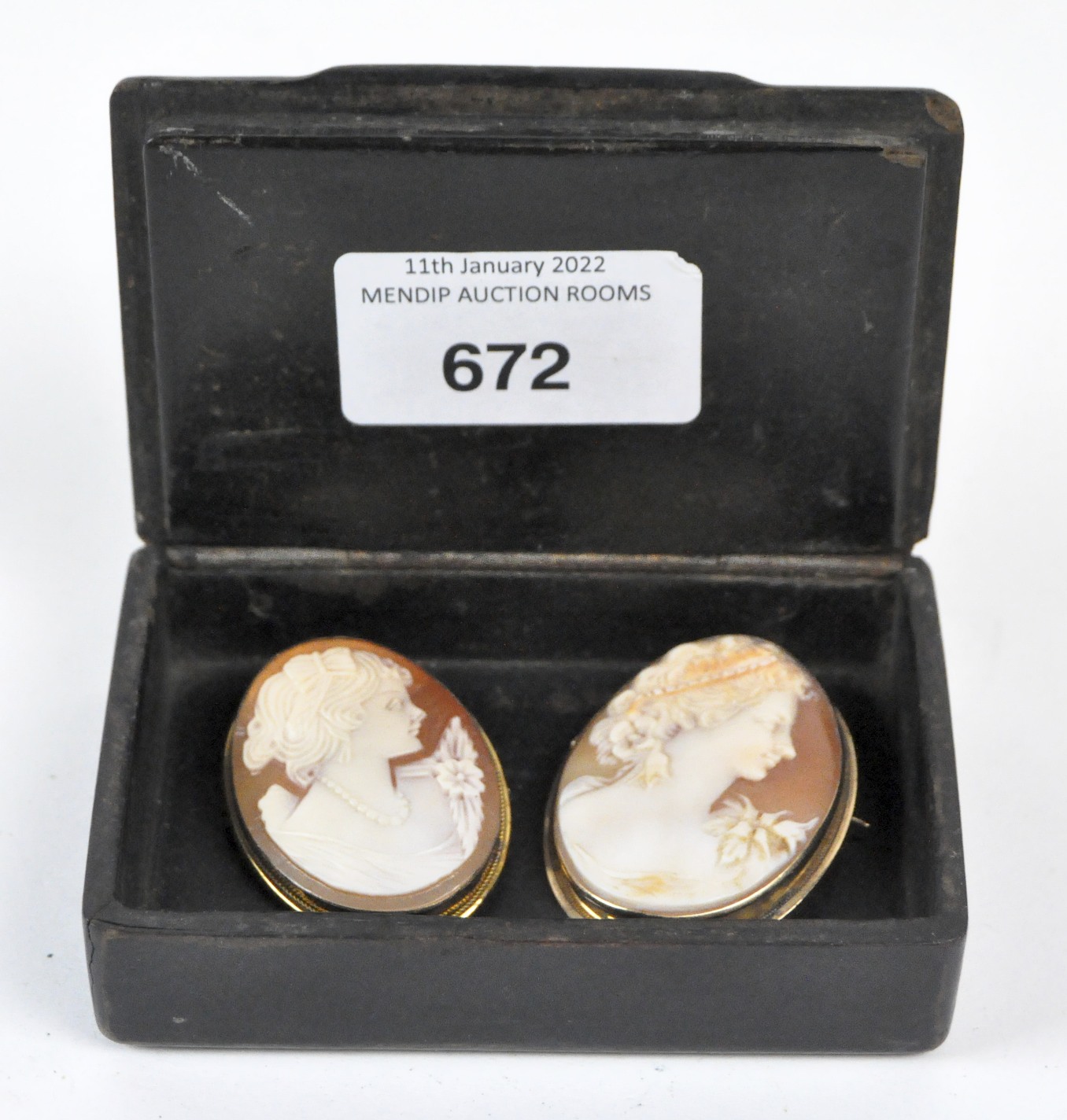 Two cameo brooches and a papier mache box, the carved cameo brooches both featuring female profiles,