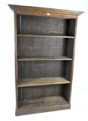 A 20th century stained pine open bookcase, containing four shelves, on a pedestal base,