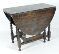 A stained wooden drop leaf table, of oval form, supported by barley twist legs,