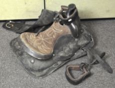 A 16 inch dark brown leather Western saddle and stirrups,