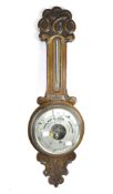 An early 20th century oak barometer with carved scroll and foliate details,