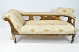 An early 20th century chaise longue with carved details, upholstered in beige and brown,