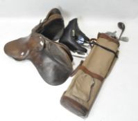 A leather horse riding saddle, a pair of vintage ice skates and a canvas golf bag and clubs