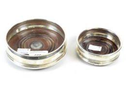 A silver wine bottle coaster and a smaller silver plated example, both with wooden bases,