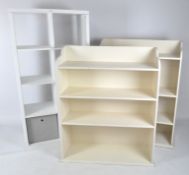 A white storage unit and two white painted bookcases,