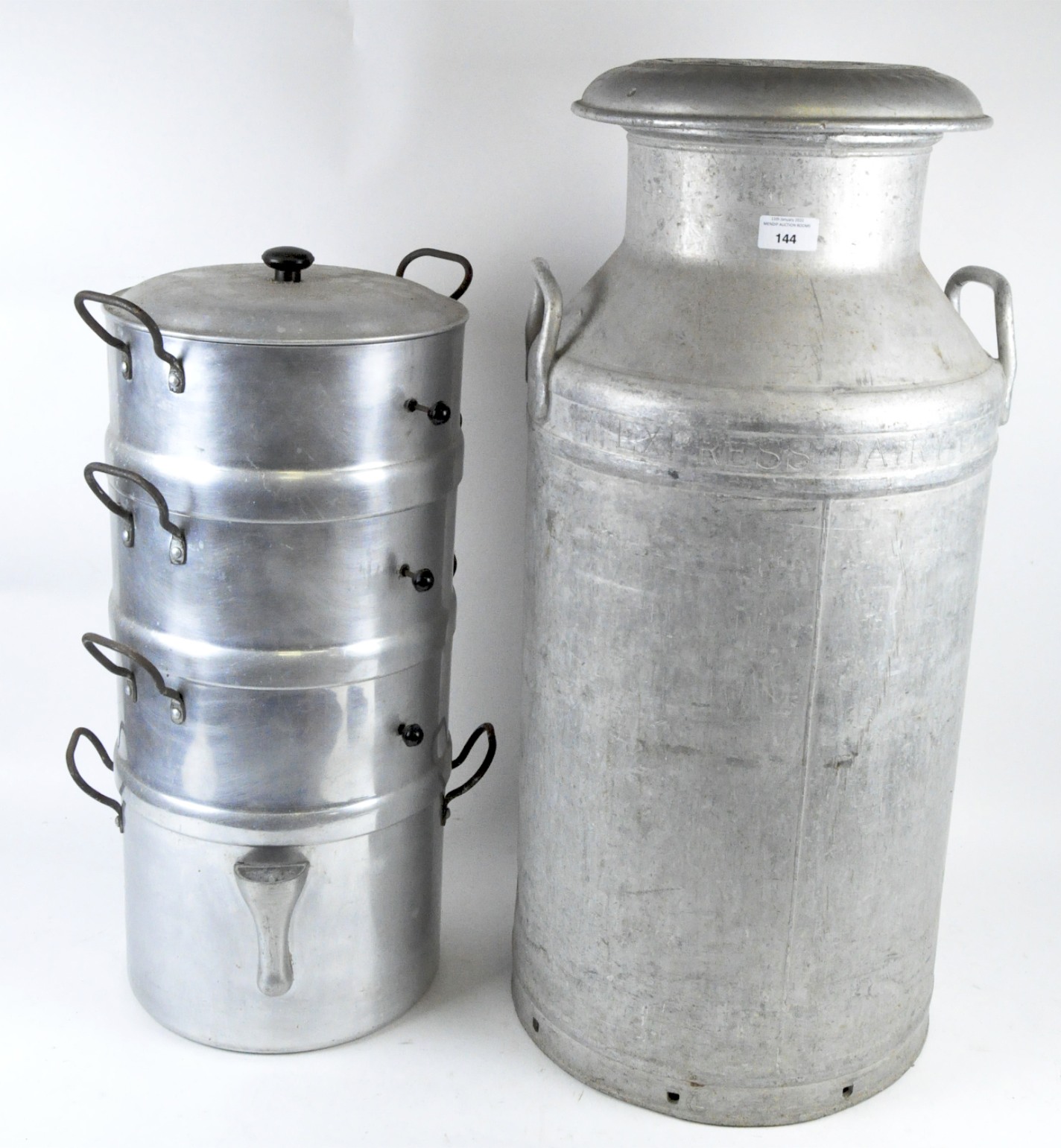 A large industrial milk churn and four cooking pots, all cast metal with handles to either side,