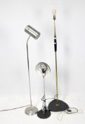 Three standing floor lamps, two of adjustable heights, the metal framed mounted on shaped bases,