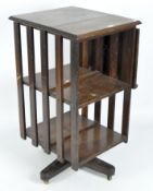 An Edwardian oak revolving two-tiered bookcase, with folding reading lectern, on casters,