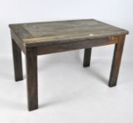A rustic oak dining table, the top comprised of planks of wood, on rectangular supports,