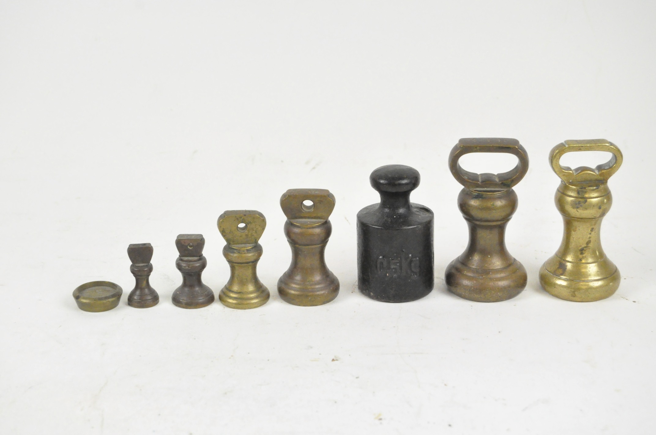 Eight antique metal weights, likely for scales,