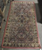 A 20th century red machine-made rug adorned with floral details throughout,