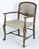 An early 20th bergère backed armchair, raised upon turned supports with cabriolet front legs,