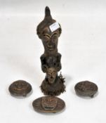 A carved wooden tribal figure, and three brass belt buckles