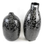 Two ceramic vases, glazed in black and decorated in swirling motifs,