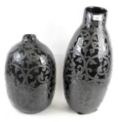 Two ceramic vases, glazed in black and decorated in swirling motifs,
