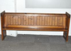 A stained pine church pew with solid side supports,