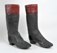 A pair of child's riding boots, in black leather with red trimming around the top,