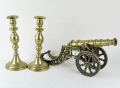 An ornamental brass canon and a pair of candlesticks,