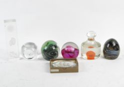 A collection of glass paperweights, including a pink Caithness example, a Mdina green example,