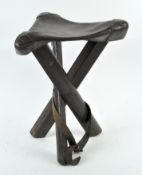 A WWI military folding stool, formed of three folding legs, with leather top,