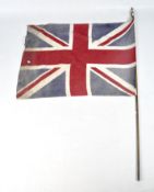 An early 20th century Union Jack flag, attached to a wooden pole,