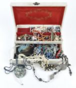 A vintage tiered jewellery box opening to reveal a selection of costume jewellery,