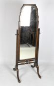 An early 20th century shaped cheval mirror suspended on fluted tapered uprights