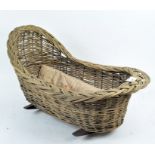 A vintage wicker dolls' crib, supported on rockers,