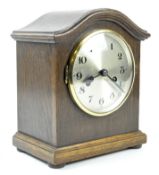 A 1930's German mantle clock, the oak cased raised upon flat bun feet,