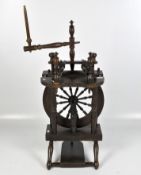 An early 19th century spinning wheel, with top wheel section, on turned supports and a raised base,