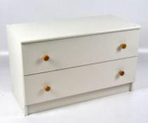 A contemporary chest of drawers, two drawers with turned pine handles, painted white,