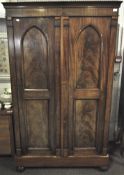 An early 20th century two door wardrobe, with veneered panels to the front, raised on bun feet,