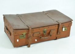 A vintage brown leather suitcase, with a carry handle to the top and brass locks and clasps,