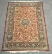 A large Persian style woven floor rug, the central panel with floral designs on a red ground,