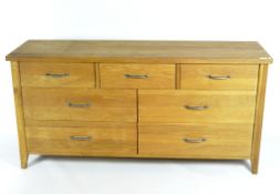 A contemporary oak sideboard, fitted with seven drawers, on tapered supports,