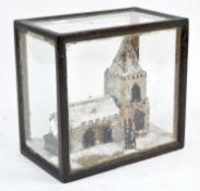 A handmade scene of a church in the snow, contained within a glass box,