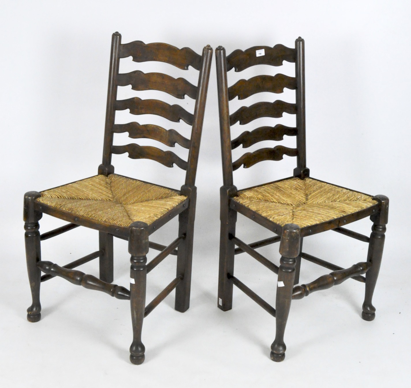 Two ladderback dining chairs with rush seating, on turned supports and bun feet,