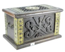 A small wood chest, deeply carved to the front featuring a coat of arms,